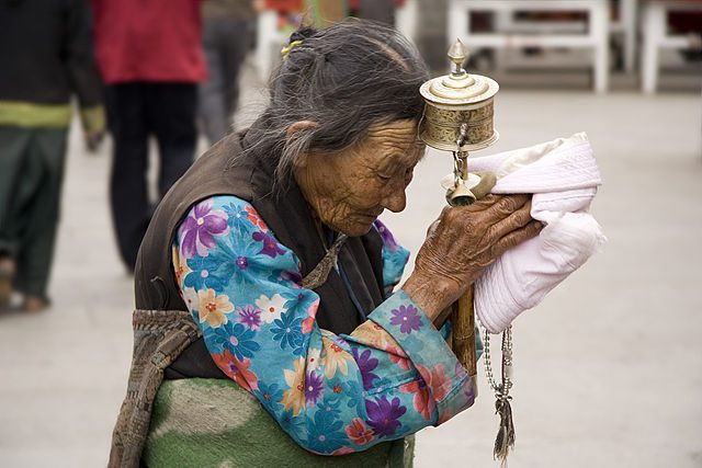 An elderly Tibetan women holding a prayer wheel on the Lhasa's pilgrimage circuit of Barkhor. Photo taken by Luca Galuzzi - https://www.galuzzi.it.