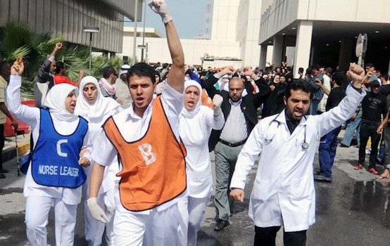 Medical staff at Salmaniya Medical Complex, march near the hospital in response to news that their paramedic crews and doctors were attacked by police after police stormed the protest site in Lulu Square in Manama, Bahrain 17 February 2011. At least three demonstrators were killed early 17 February during the police attack on protesters who were pushing for government reform.