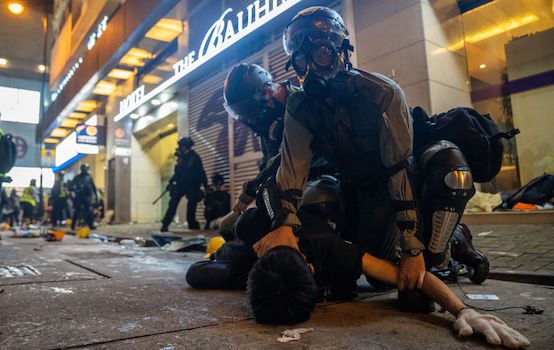 Riot police officers hold a demonstrator to the floor as