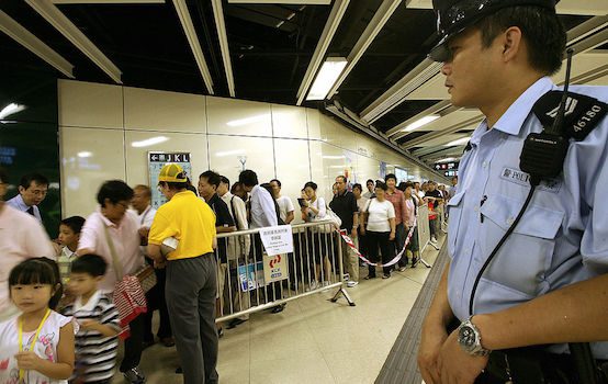 A policeman looks on as people queue up