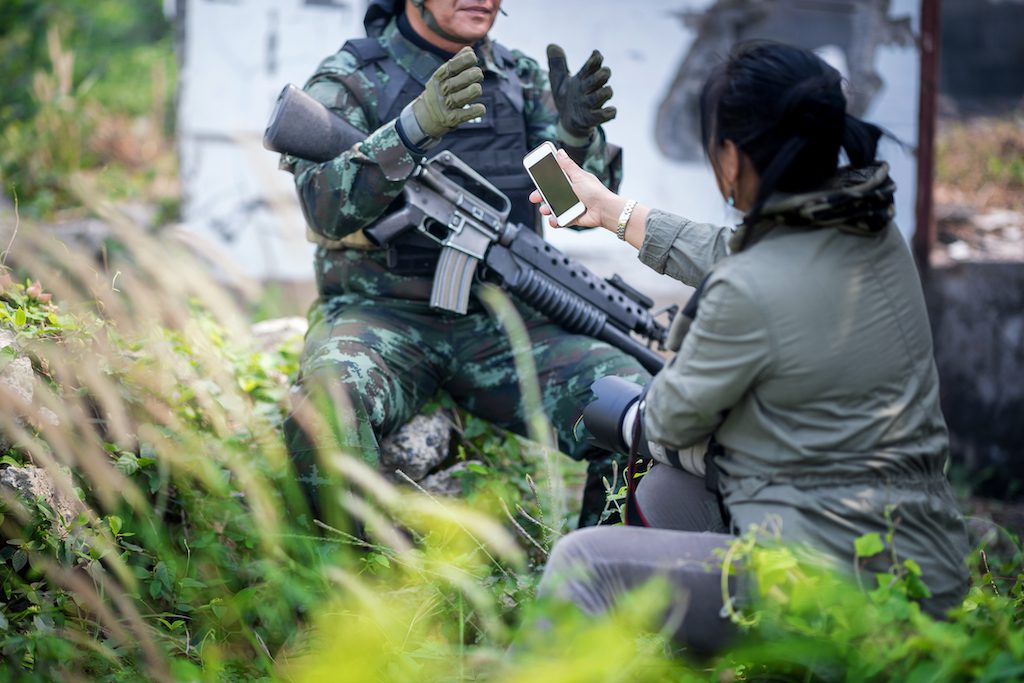 Female journalist interview soldier during war conflict. Photojournalist  work on gress field concept.