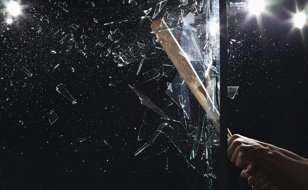 Detail of a man smashing glass with a baseball bat