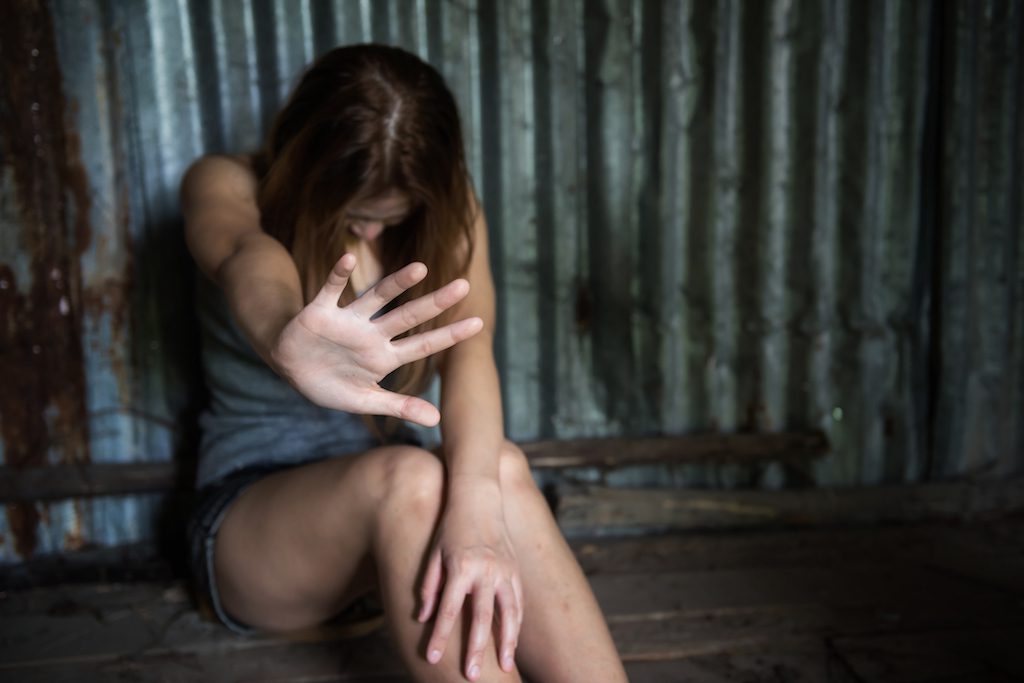 Young Woman Showing Stop Gesture While Sitting Against Metal Wall