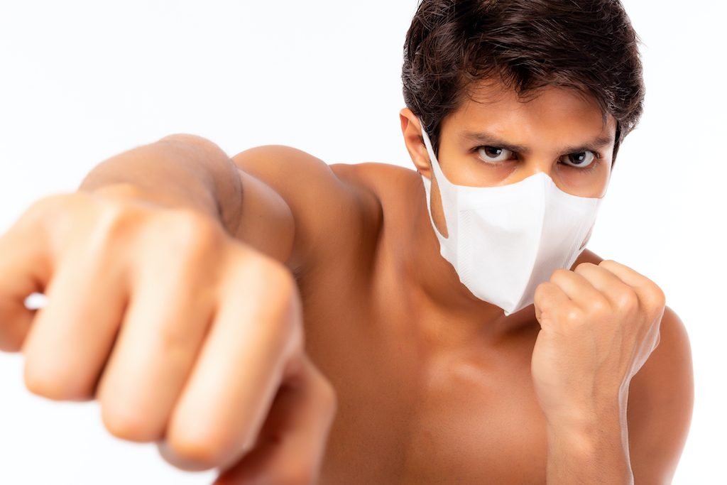 Handsome caucasian man wear face mask and fighting by punching to virus, flu, pollution, coronavirus or covid-19, illness. Cool guy get confidence, determined for fighting with sickness or viruses