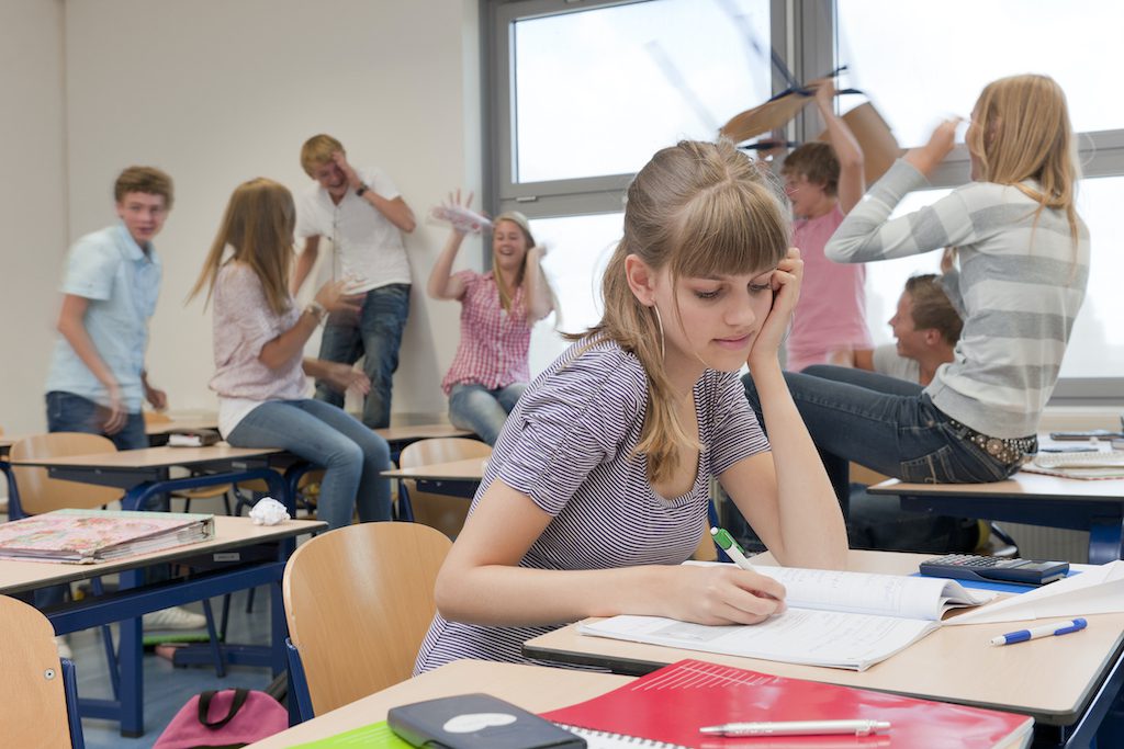 sad high school girl in chaotic classroom