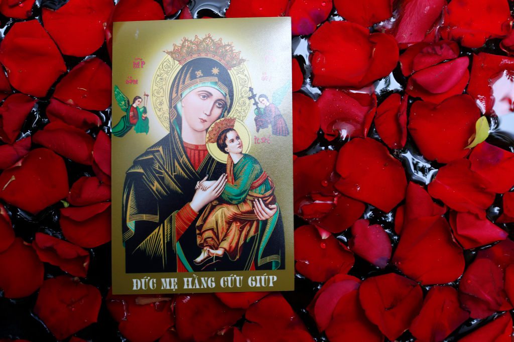 Holy image of Virgin Mary and Child on red roses.