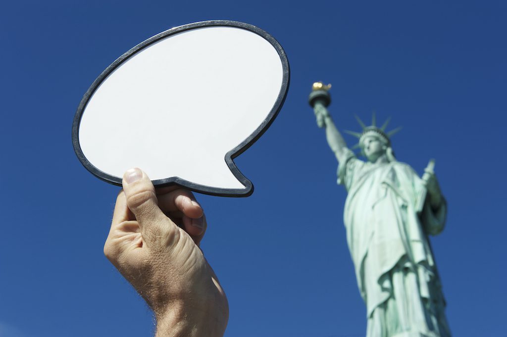 Hand Holds Blank Speech Bubble Above Statue of Liberty