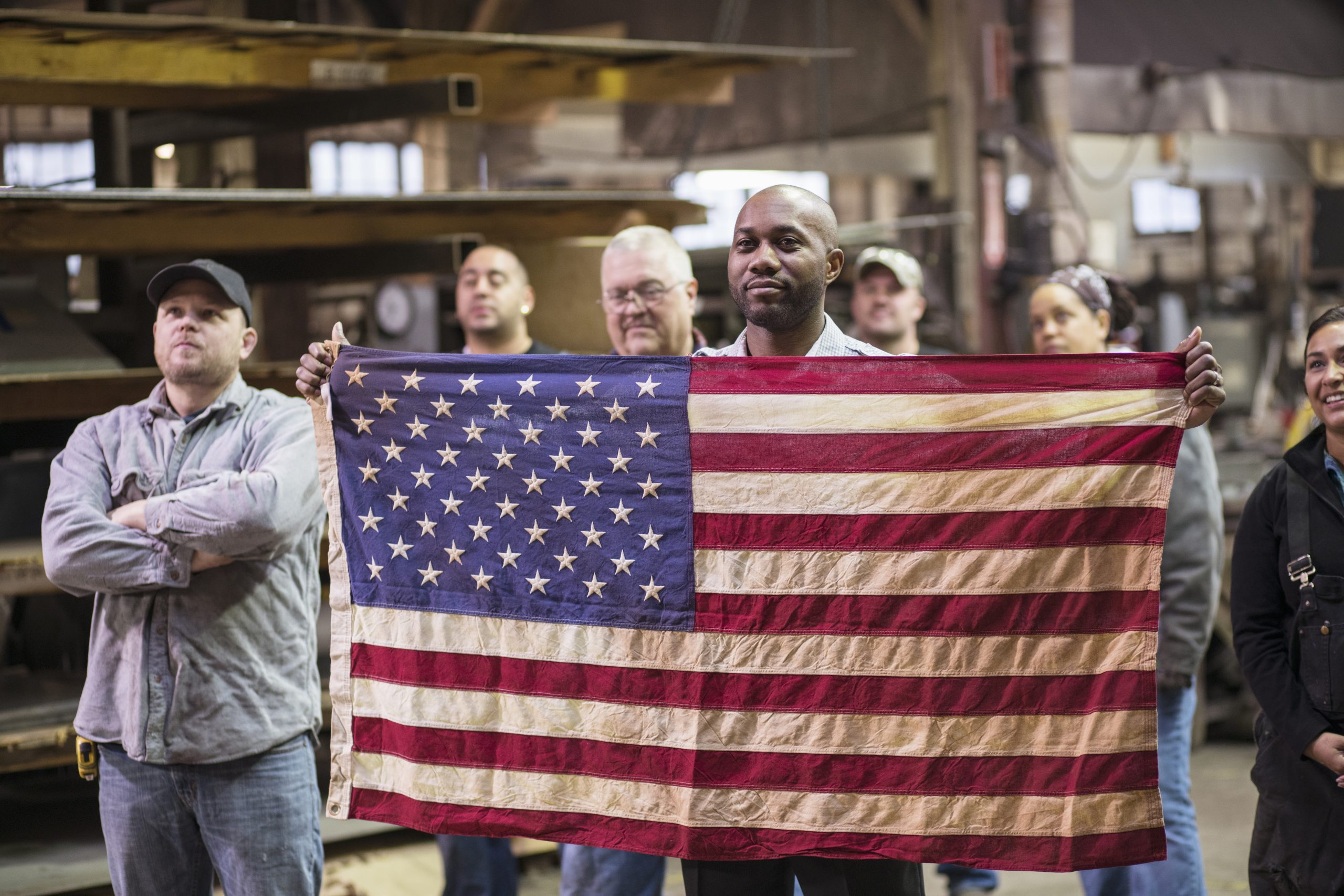 Workers holding American flag in factory