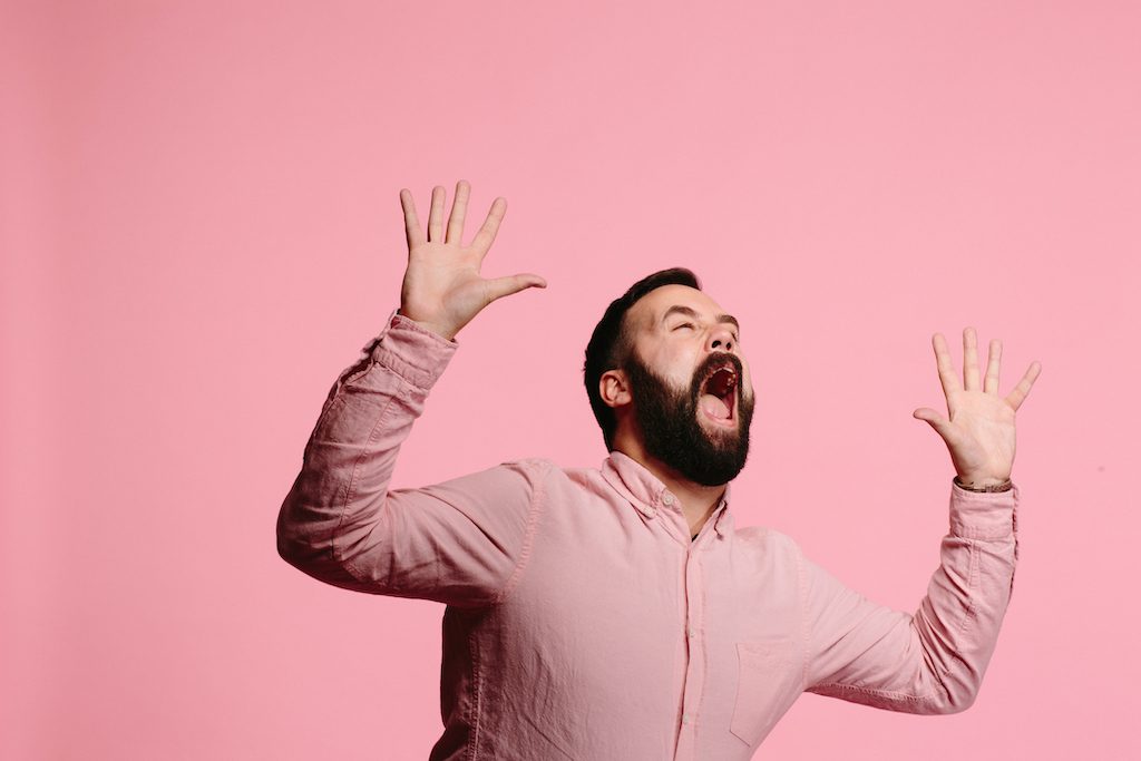 Screaming man with beard and both arms up