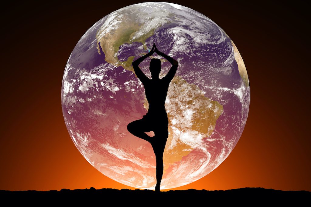 Silhouette of women doing yoga on the background of the planet Earth.