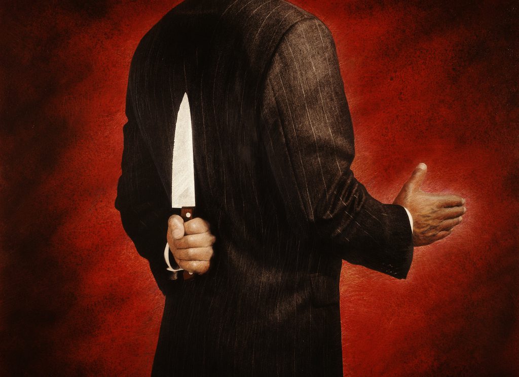 BUSINESSMAN WITH KNIFE BEHIND BACK
