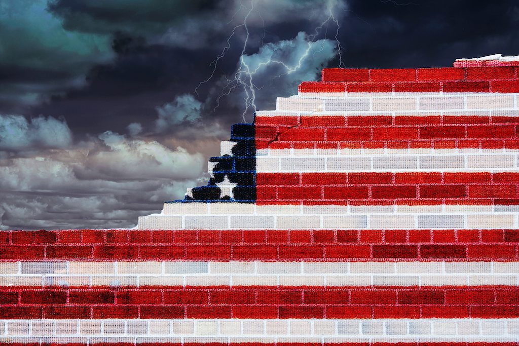 broken brick wall with American flag design and stormy sky