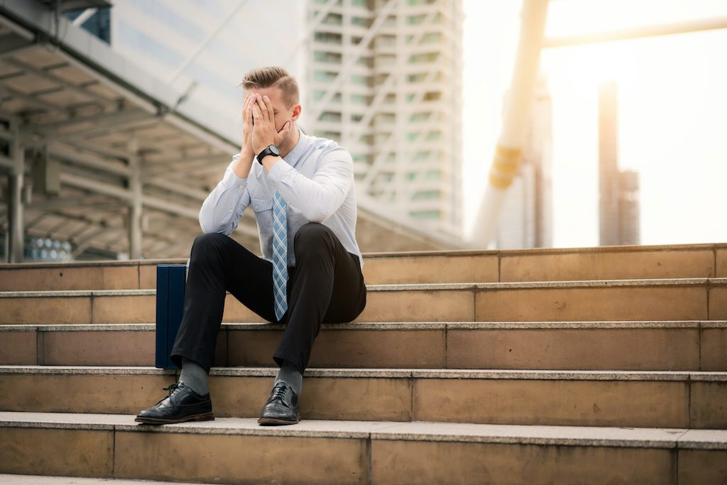 Young business man crying abandoned lost in depression sitting on ground street concrete stairs suffering emotional pain, sadness, looking sick in grunge lighting