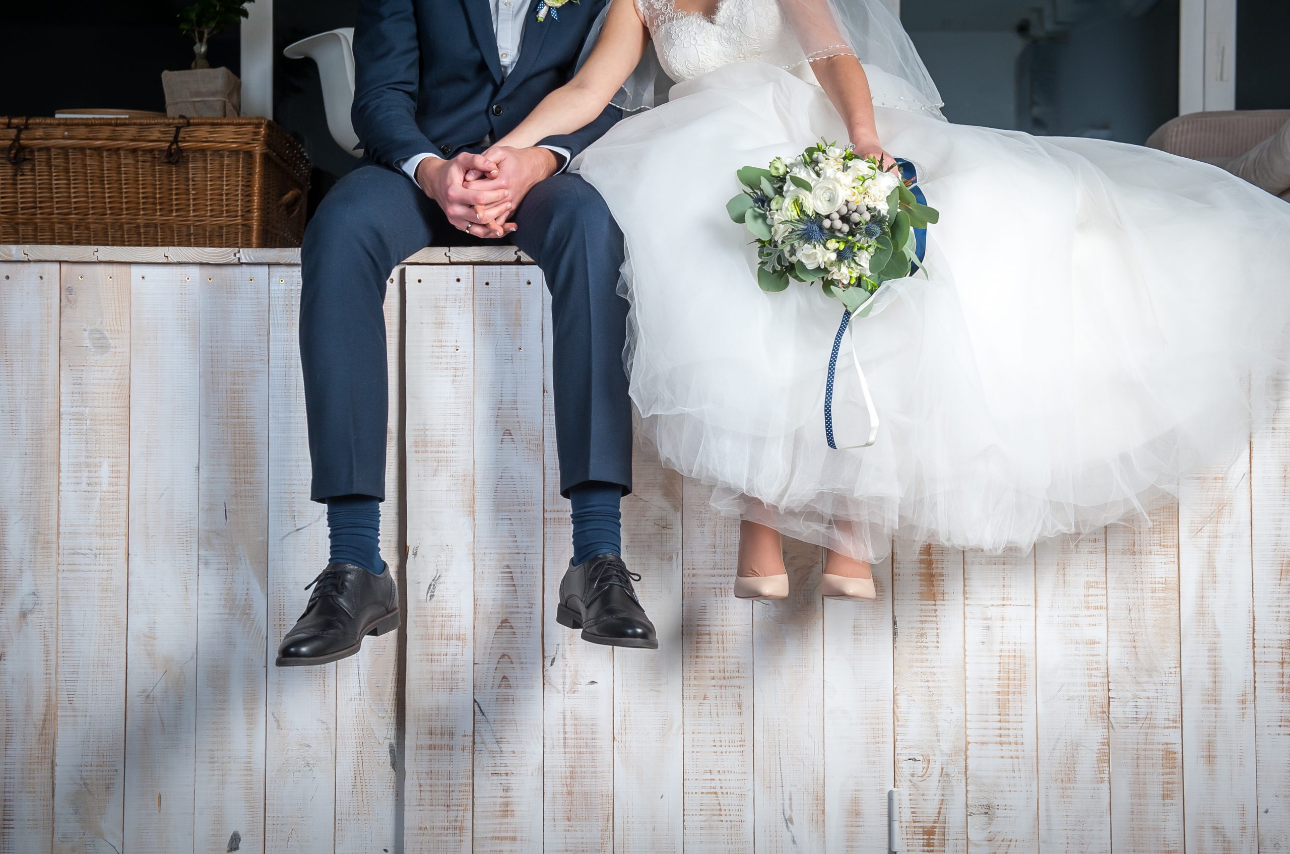 Beautiful,Wedding,Couple,Sitting,On,Wooden,Pier,,Swung,Their,Legs