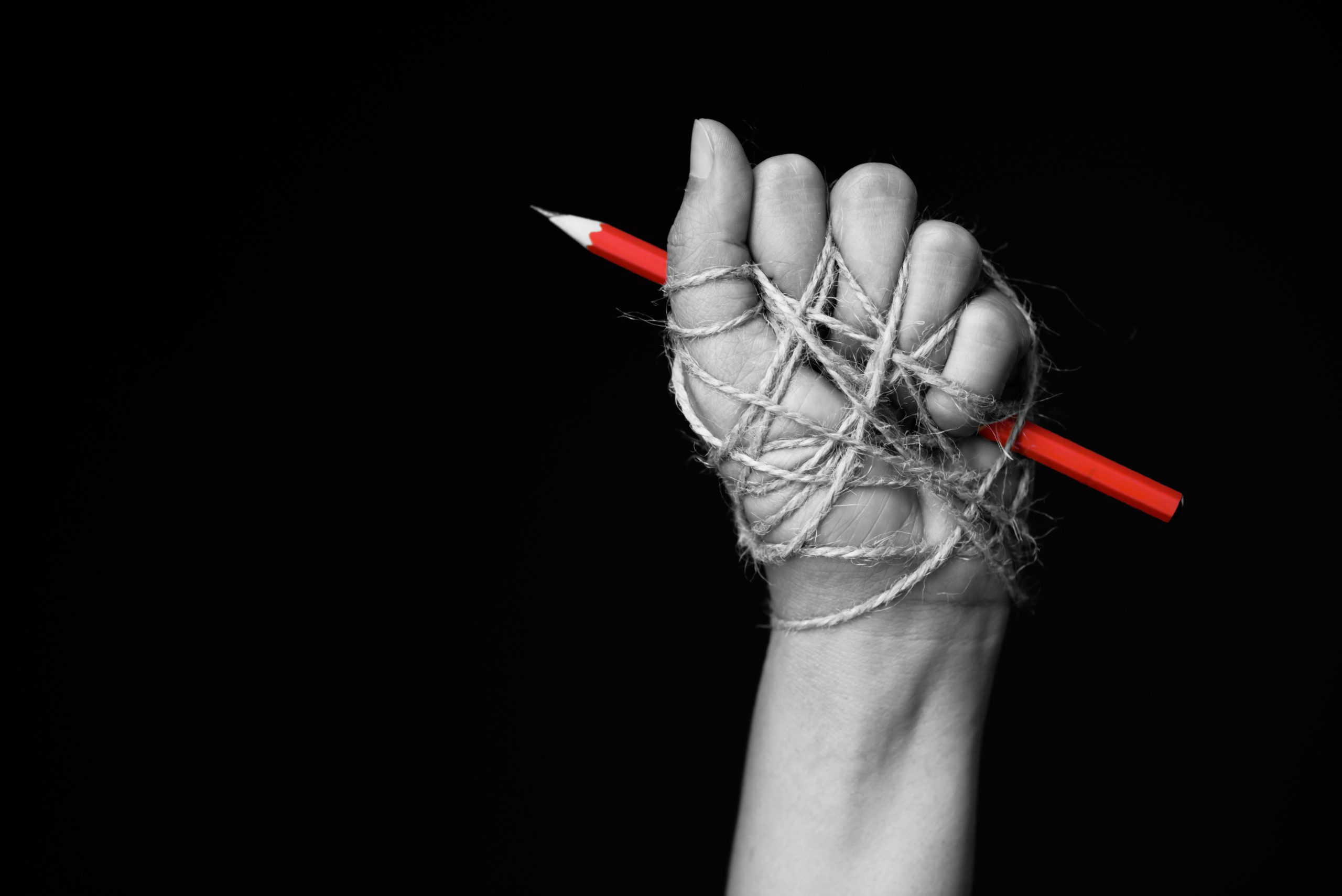 Hand,With,Red,Pencil,Tied,With,Rope,,Depicting,The,Idea