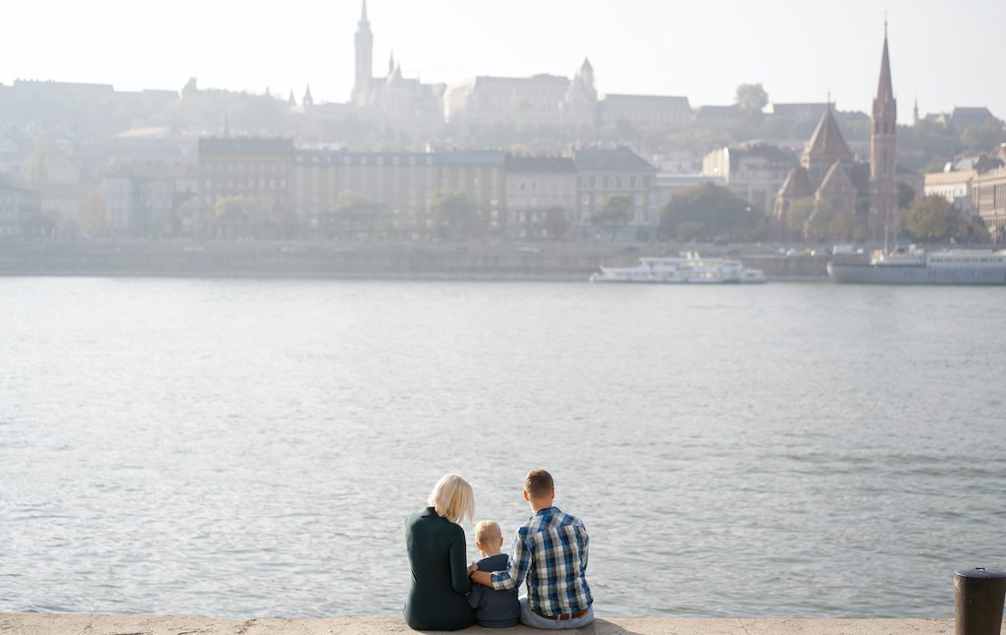 A,Young,Family,Of,Tourists,Sits,On,A,Stone,Parapet