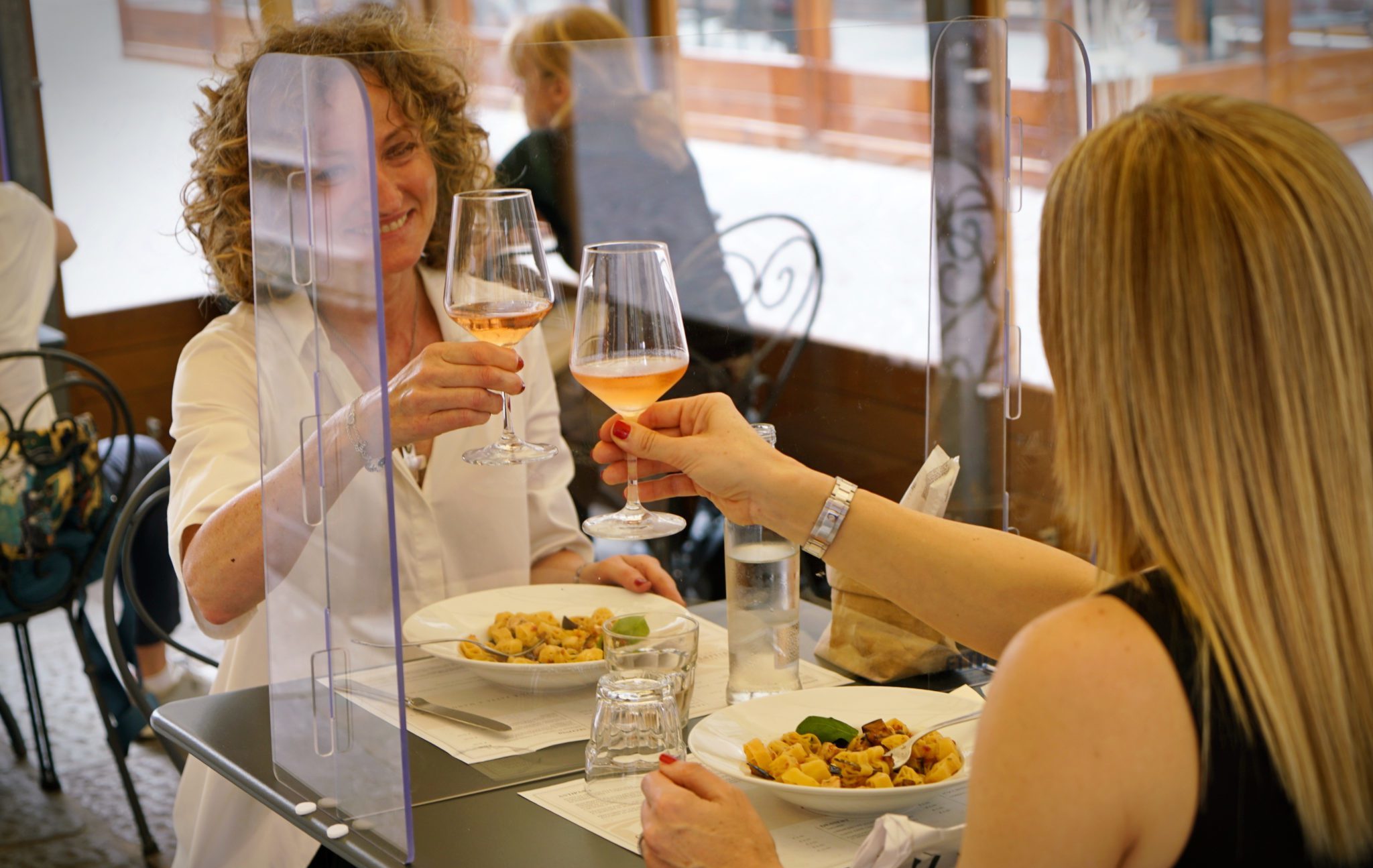 Women,Sitting,In,Restaurant,Eating,Food,With,Table,Shield,To