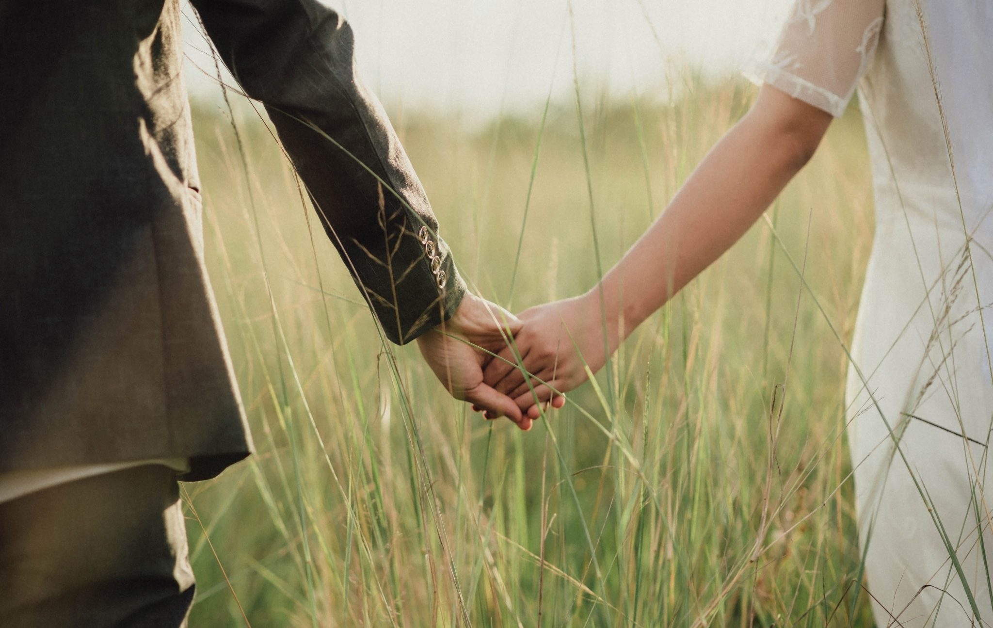 Young,Asian,Couple,Holding,Hands,And,Walking,In,The,Meadow