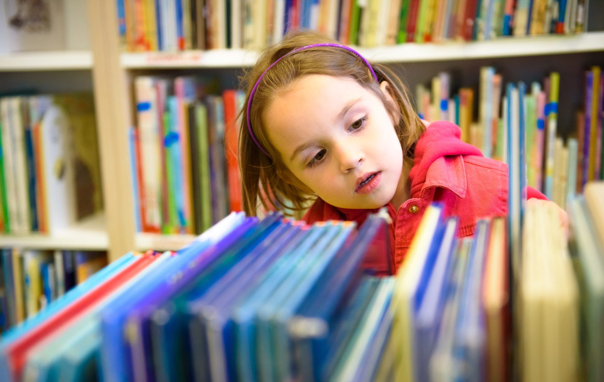 Little,Girl,Is,Choosing,A,Book,In,The,Library.,A