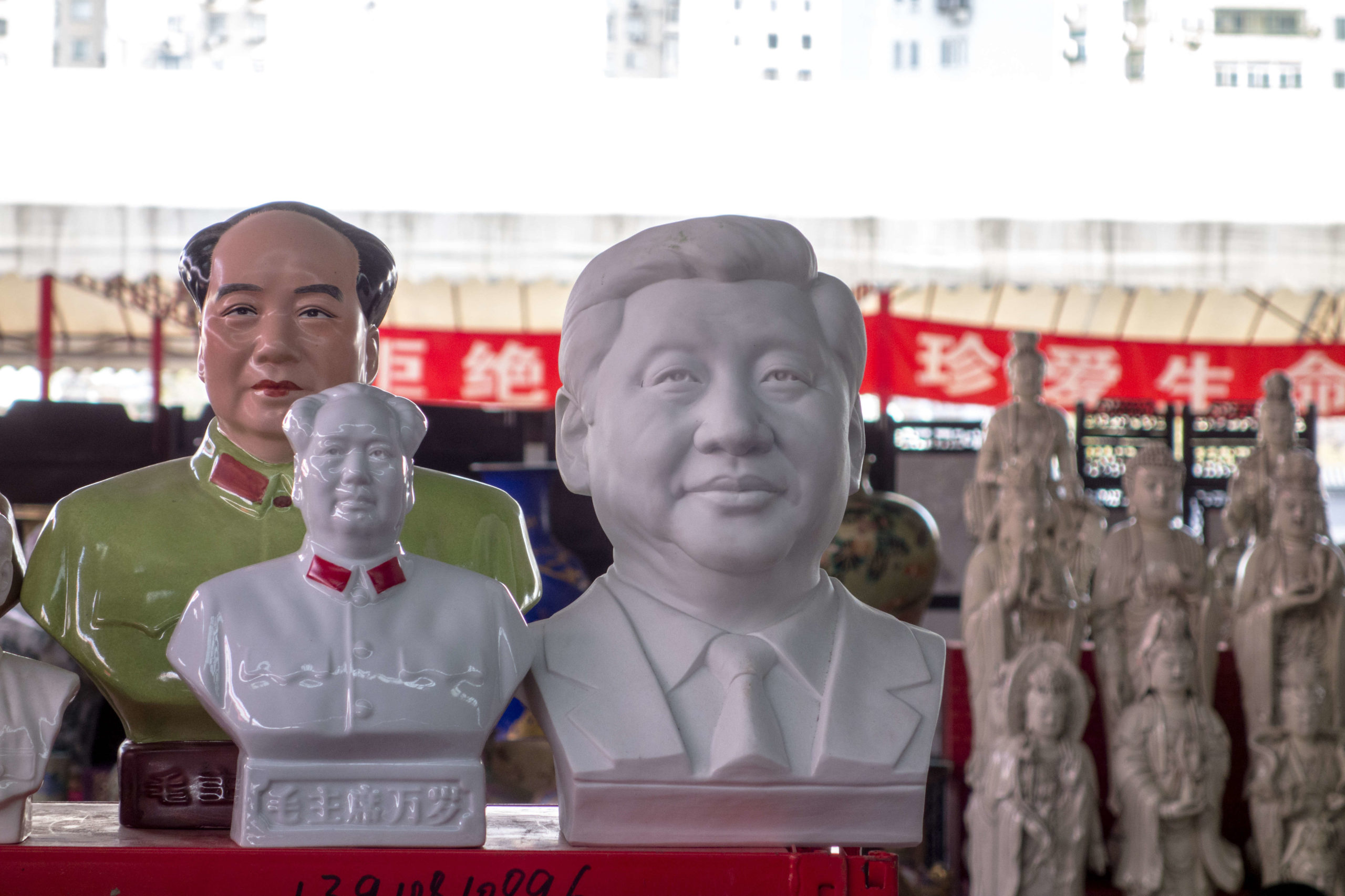 Porcelain statue of Mao Zedong and Xi Jinping on a stall.