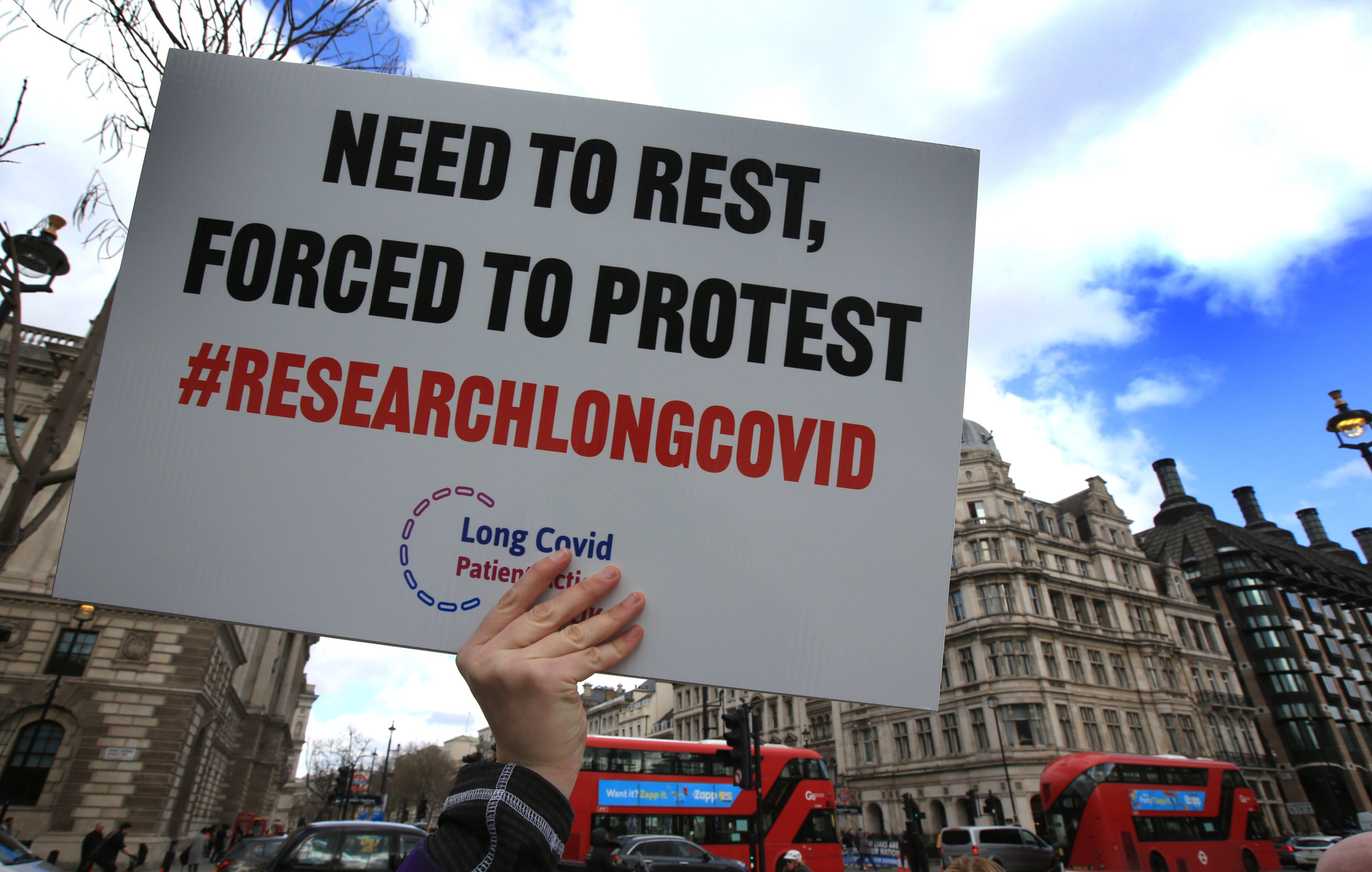 A protester holds up a placard demanding research into Long