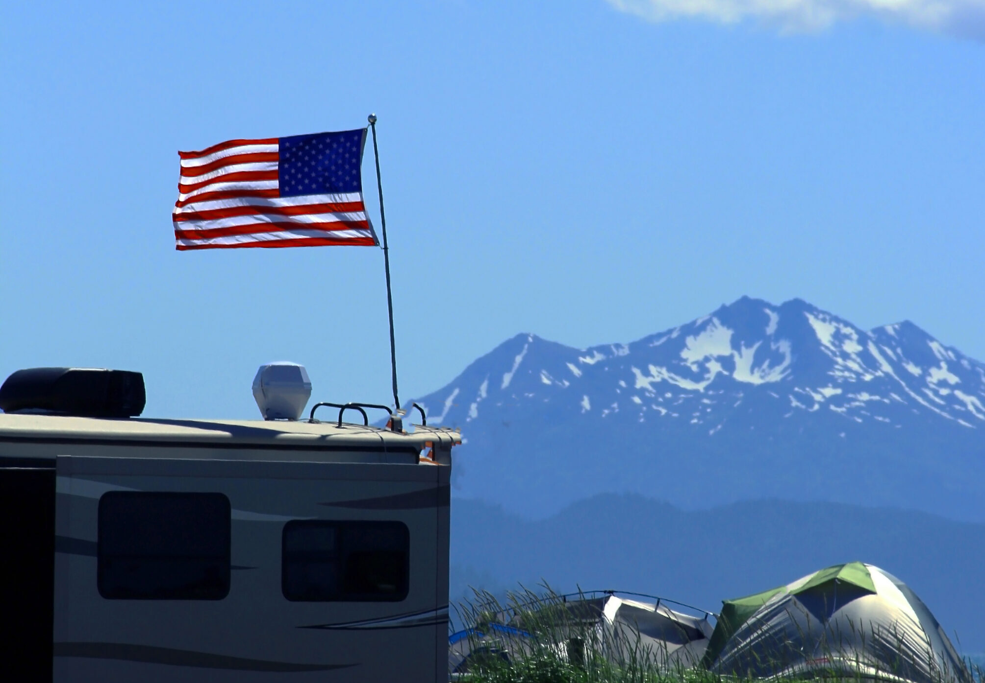 American,Flag,Over,Rv,With,Tent,And,Mountains,In,The