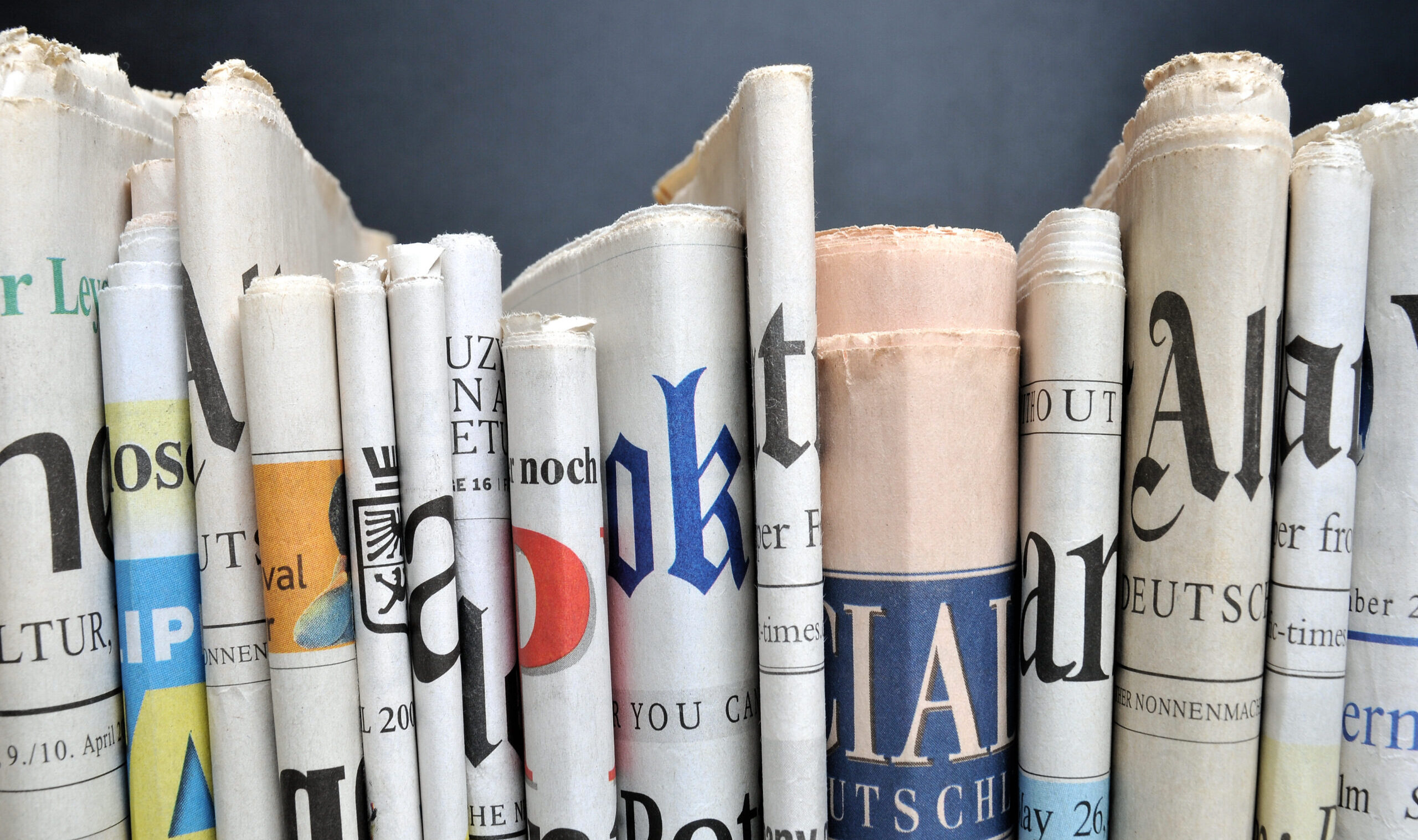 News,-,Folded,Newspapers,In,Front,Of,Black,Wall