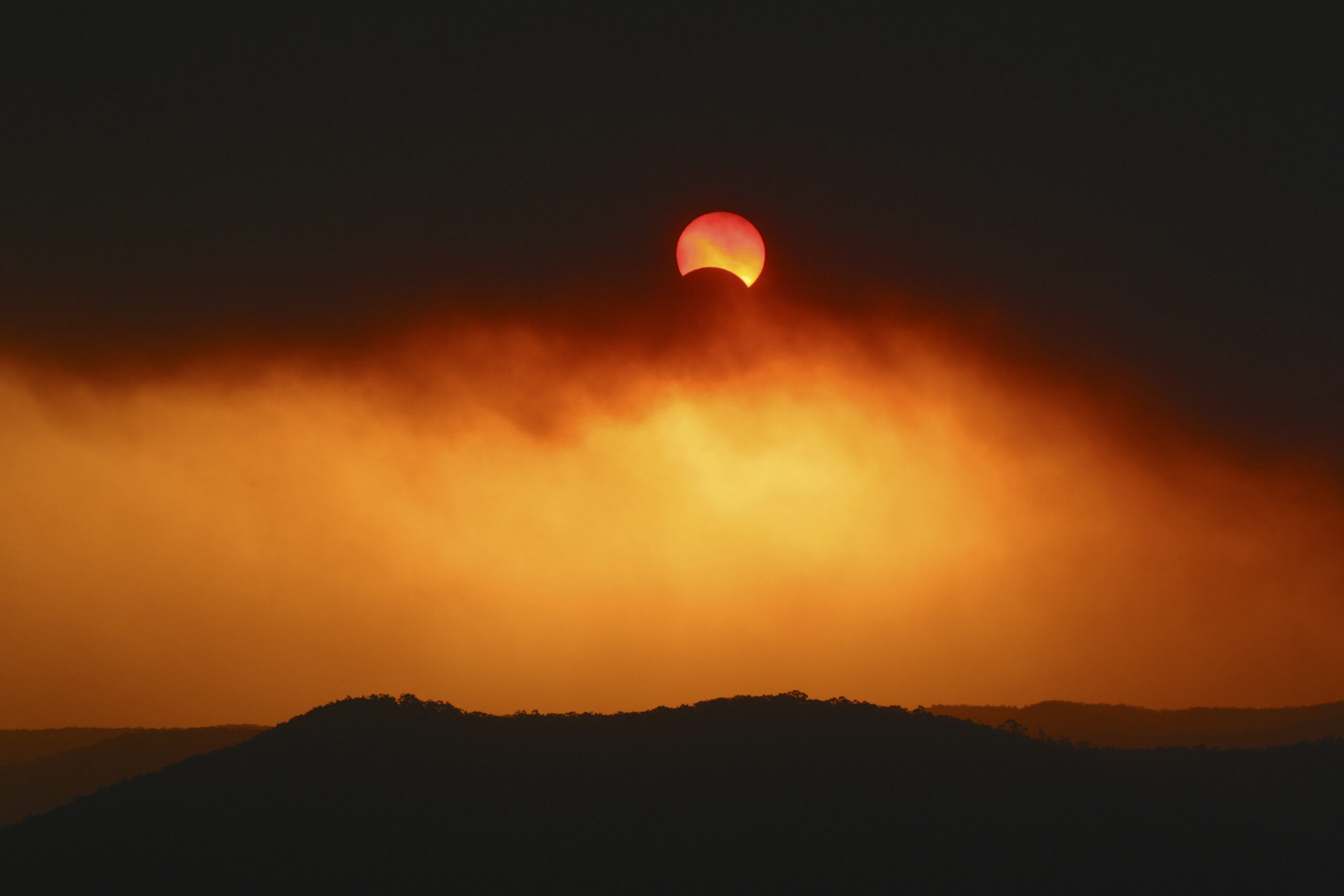 Partial solar eclipse on 04/12/2002 through thick plume of bushfire smoke over Broken Bay.